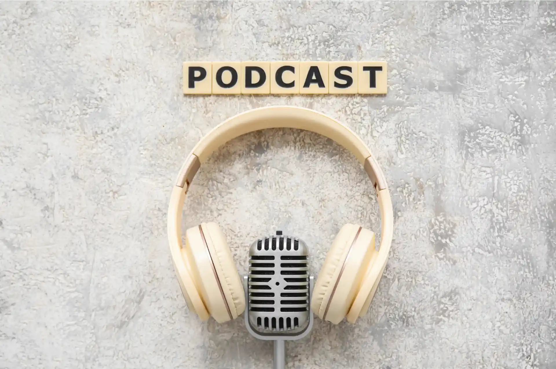 White headphone around a silver microphone and letters saying "podcast"